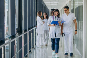 Zwei medizinische Fachkräfte besprechen in einem Krankenhausflur eine Akte – „Von der Stationsleitung an die Klinikleitung“.