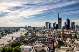 Stadtpanorama mit modernen Wolkenkratzern, historischen Gebäuden und Business Coaching Frankfurt am Flussufer.