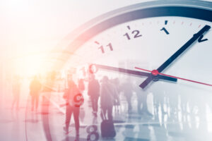 Eine große Uhr, die über eine Menschenmenge in einem hellen Innenraum gelegt ist und das Resilienztraining für Führungskräfte symbolisiert.